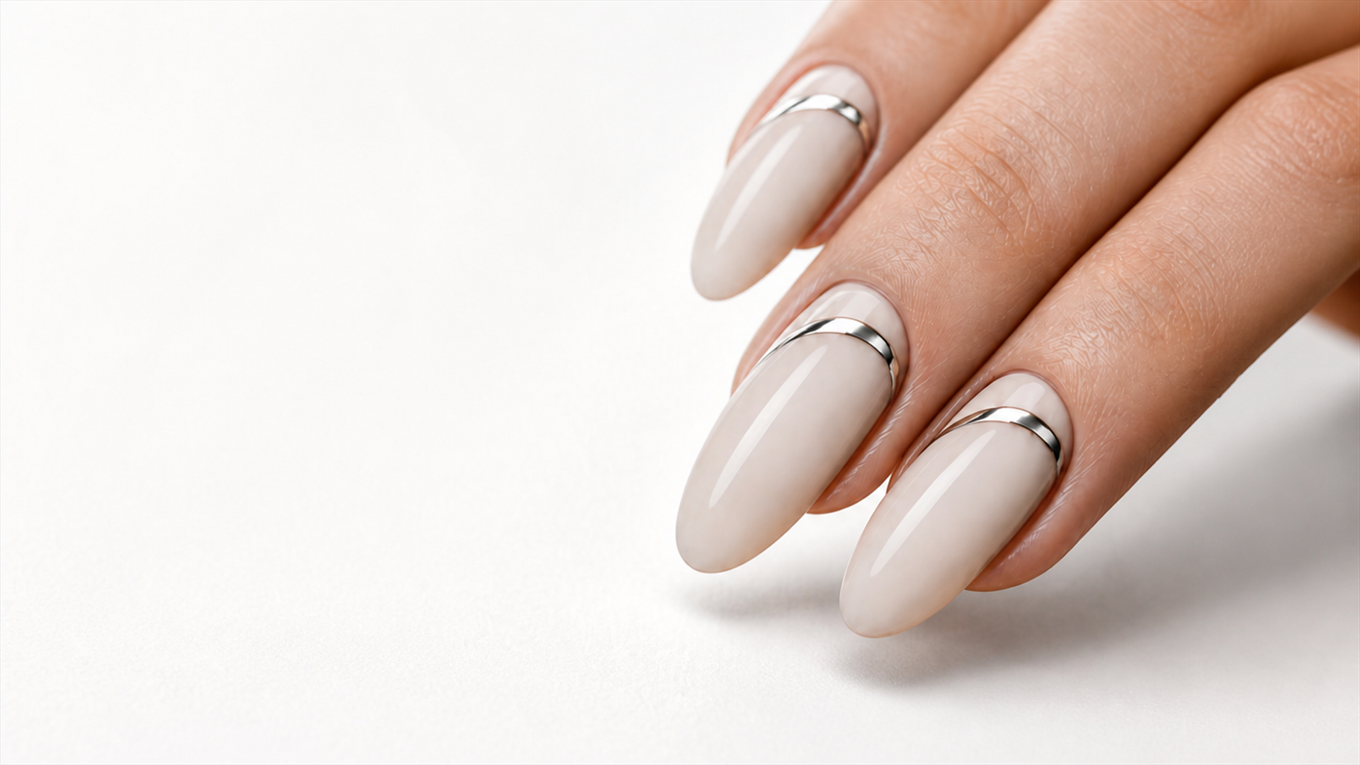 Close-up of almond nude nails finished with fine chrome rings