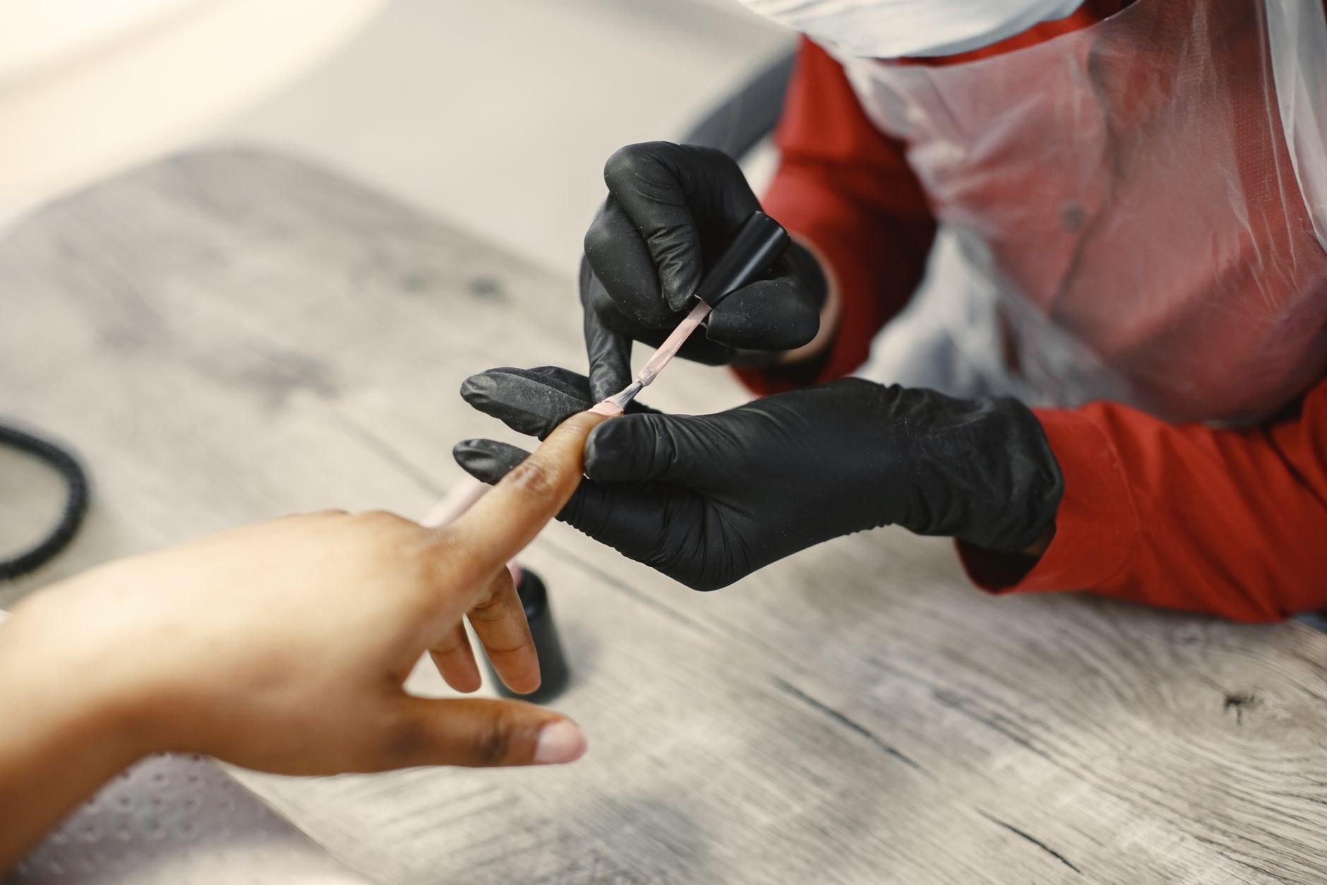 Nail artist painting nails in black gloves, close detail